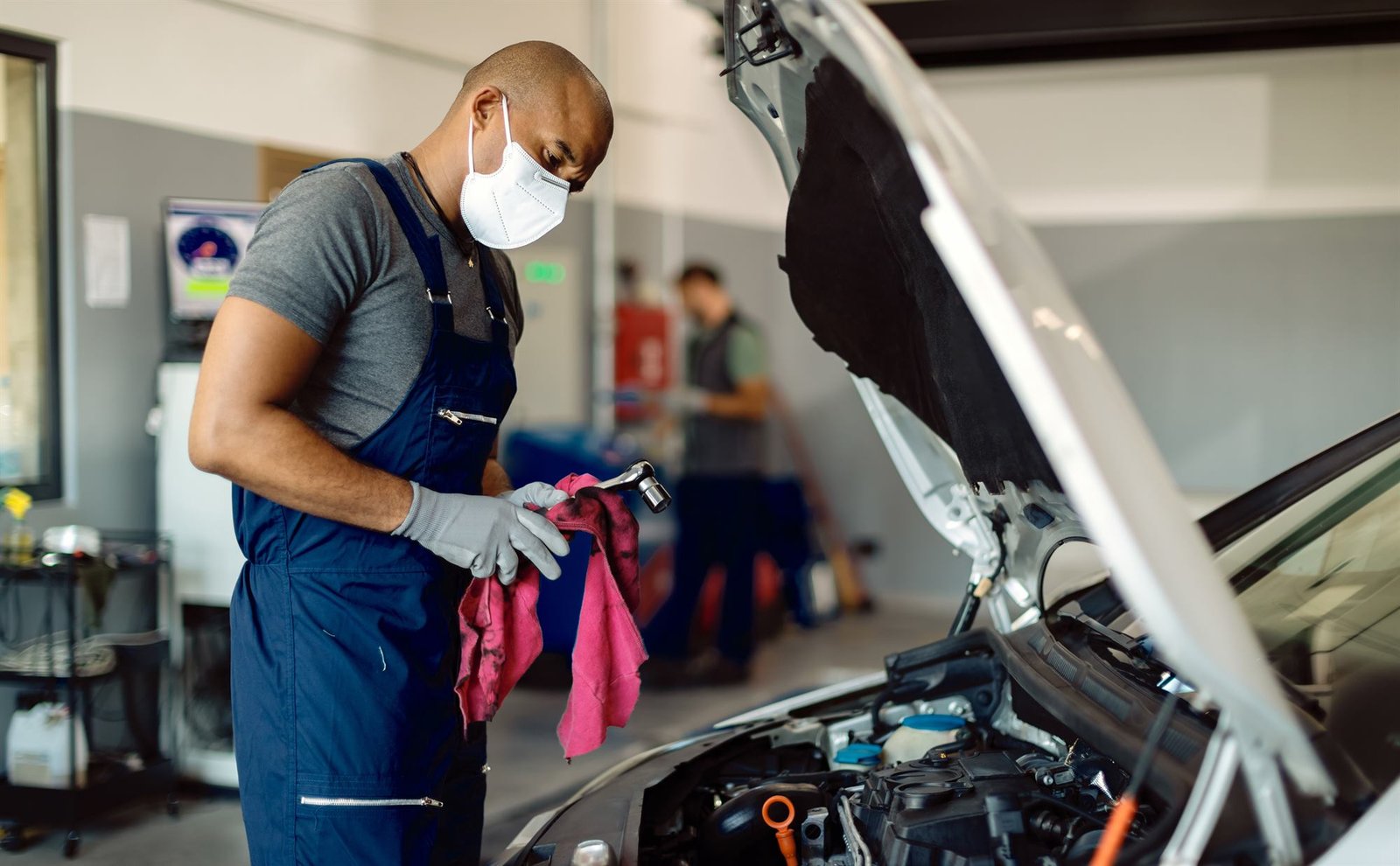 Mécanicien du garage inspectant un moteur, capot ouvert